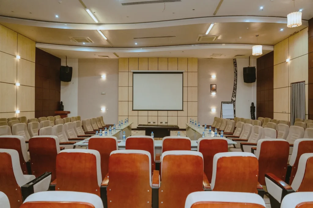 Conference hall with red and cream chairs facing a projection screen