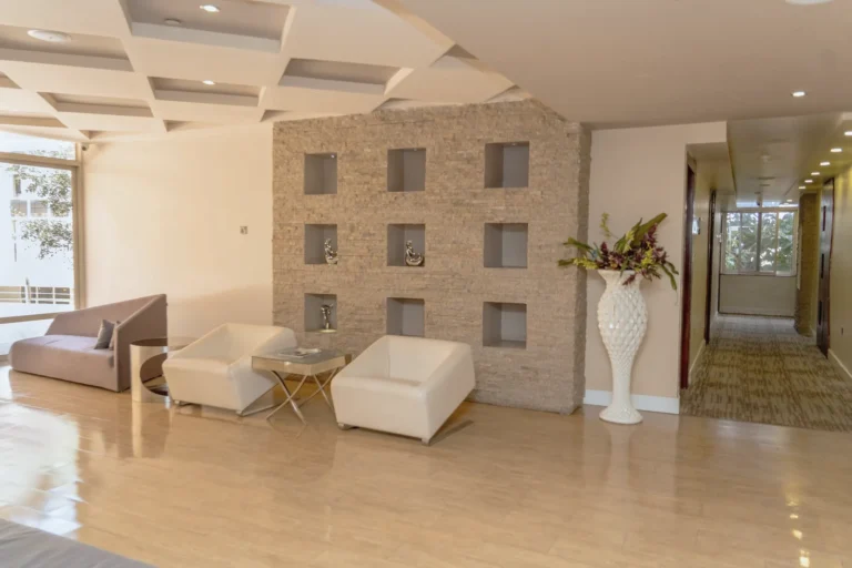 Upper landing with a stone niche wall, white vases and the metal SG logo